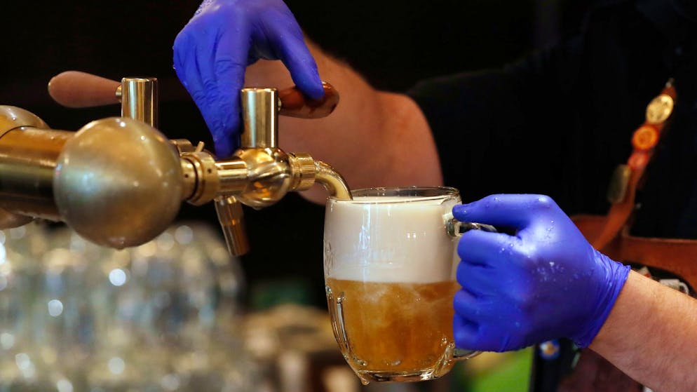 Ein Barkeeper zapft ein Bier auf einer Restaurant-Terrasse. 