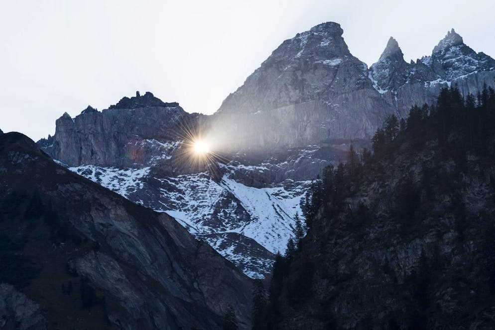 Die Sonne scheint durchs Martinsloch in den Tschingelhörnern auf das Dorf und die Kirche. Ein gewaltiger Felsabbruch hat nun den Weg dorthin versperrt.