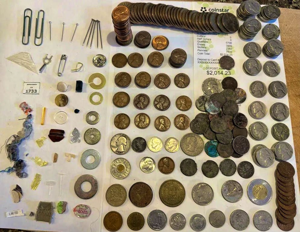 Questa immagine mostra tutte le monete storiche e alcuni oggetti di uso quotidiano trovati nel vaso.