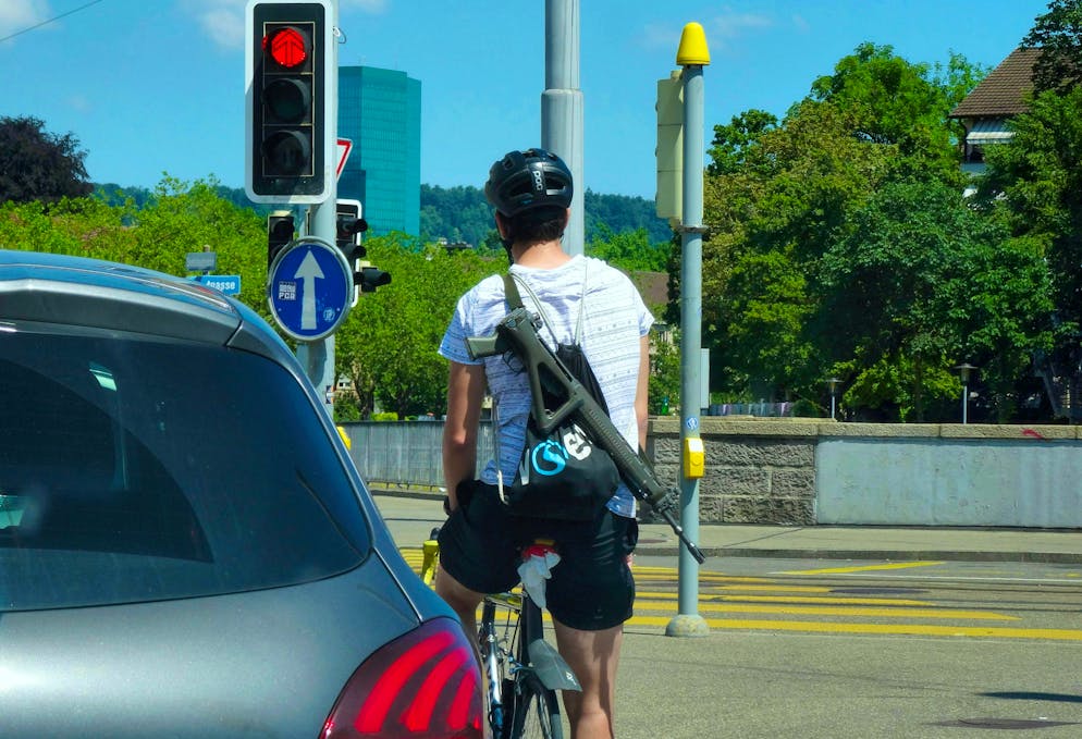 Cyclist with a Swiss assault rifle on his back. In future, shooters from towns near the border will have to take a detour if they want to go to the nearest shooting range.