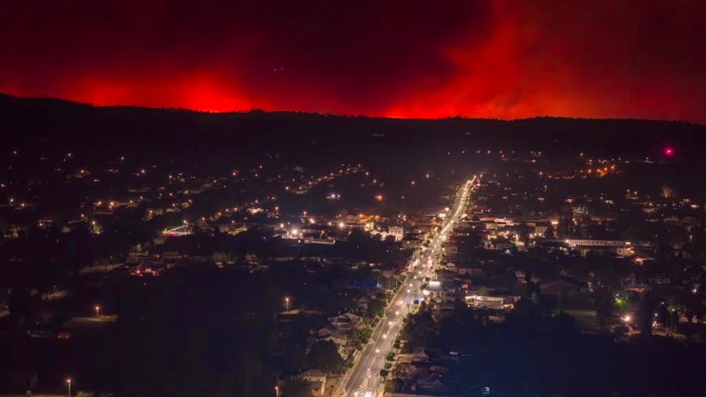 Australien, Tenterfield: Flammen und Rauch von Buschbränden steigen hinter dem Stadtzentrum empor. Die Sorge vor verheerenden Waldbränden in Australien wächst.