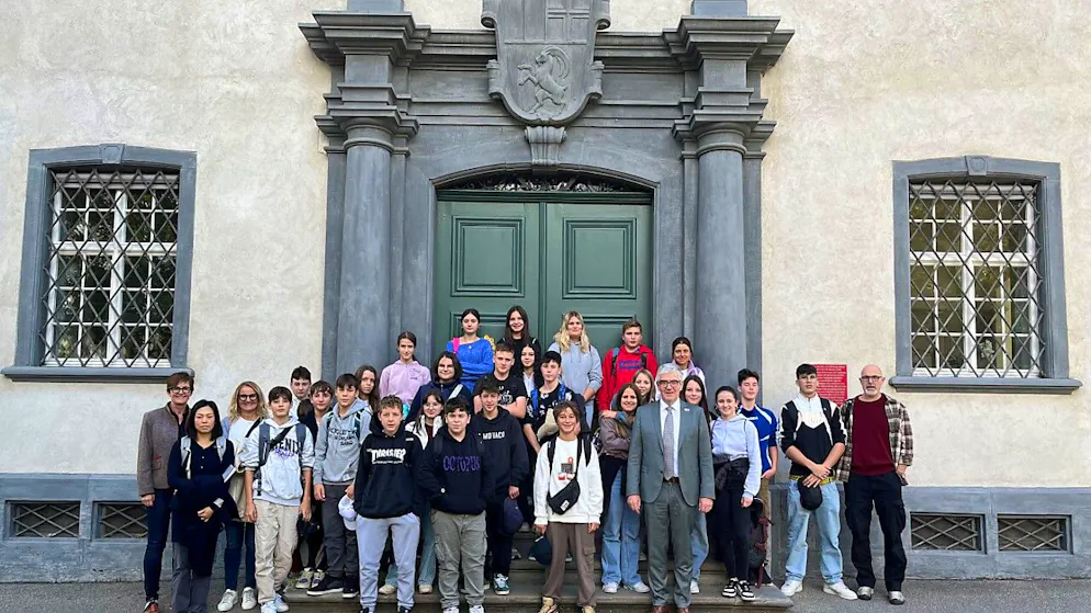 La classe del grado superiore di Stampa posa davanti all'edificio del Governo grigionese assieme al Presidente Jon Domenic Parolini.