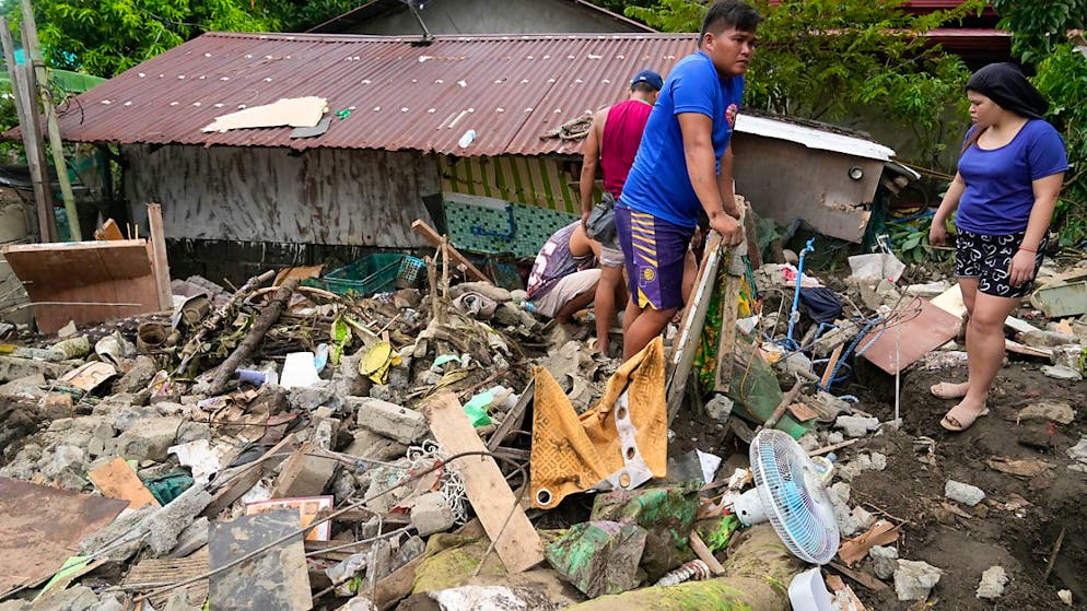 Bewohner sammeln Habseligkeiten aus ihren zerstörten Häusern nach einem durch den Tropensturm Trami ausgelösten Erdrutsch in Talisay, Provinz Batangas, Philippinen. Foto: Aaron Favila/AP/dpa