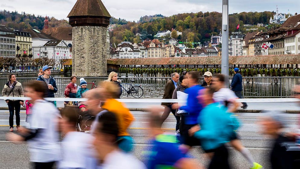 Läuferinnen und Läufer rennen während des Swiss City Marathons über die Seebrücke mit der Kapellbrücke im Hintergrund. (Archivaufnahme)