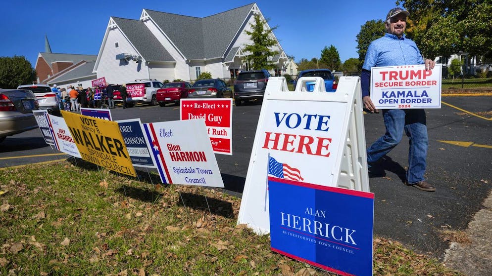 Early voting: Ein Trump-Anhänger platziert Schilder vor einem Gebäude in Rutherfordton, North Carolina, in dem bereits abgestimmt werden kann.