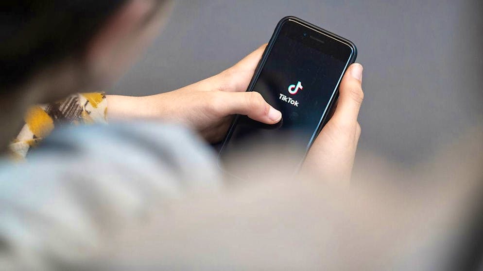 ARCHIVE - A teenager looks at a smartphone with the Tiktok logo displayed. Photo: Hannes P Albert/dpa