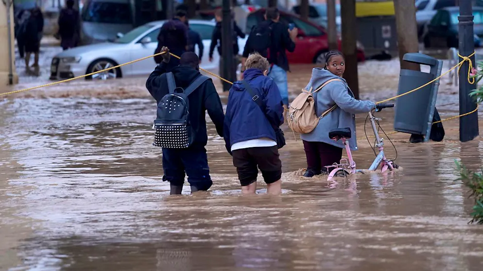 Menschen gehen durch überflutete Strassen in Valencia. Foto: ALberto Saiz/AP