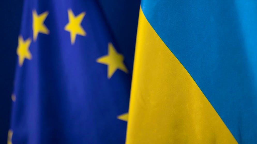 ARCHIV - Die Fahne der Ukraine steht vor der Flagge der europäischen Union. Foto: Christoph Reichwein/dpa