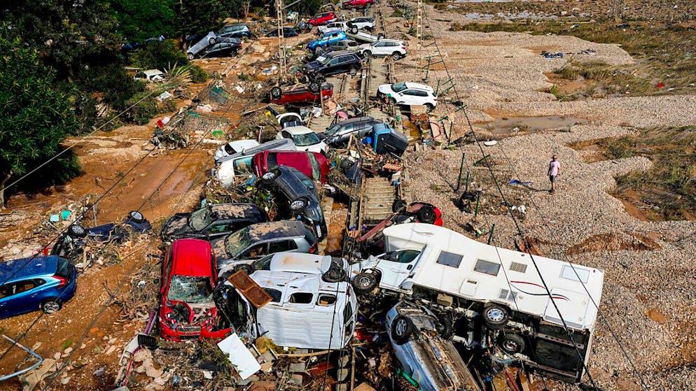Ein Mann steht neben Autos, die nach dem Unwetter übereinander liegen. Foto: Manu Fernandez/AP/dpa