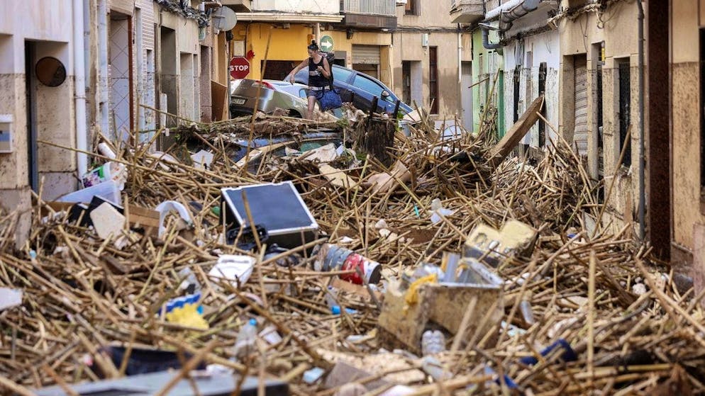 A woman climbs over debris left behind by the floods in the municipality of Paiporta. (October 30, 2024)