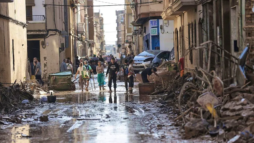 Residents walk through a street damaged by flooding in the municipality of Catarroja, Valencia.