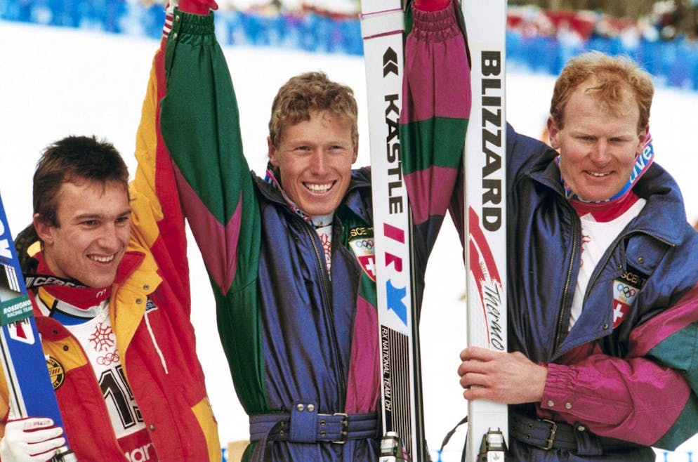 Die Schweizer Pirmin Zurbriggen, Mitte, Gold, Peter Müller, rechts, Silber, und der Franzose Franck Piccard, links, Bronze, freuen sich im Ziel über ihre Medaillen in der Abfahrt der olympischen Winterspiele 1988 in Calgary. (KEYSTONE/Thomas Studhalter)