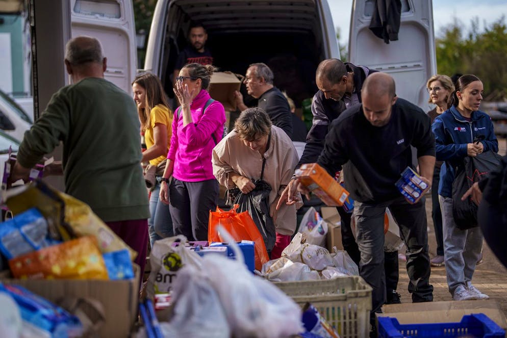 People collect food in an area affected by floods in Chiva, Spain, Friday, Nov. 1, 2024. (AP Photo/Manu Fernandez)