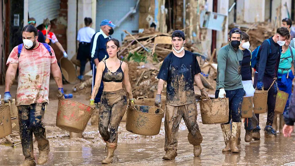 Volunteers carry buckets of mud during the clean-up in Paiporta near Valencia in Spain. Photo: Hugo Torres/AP/dpa