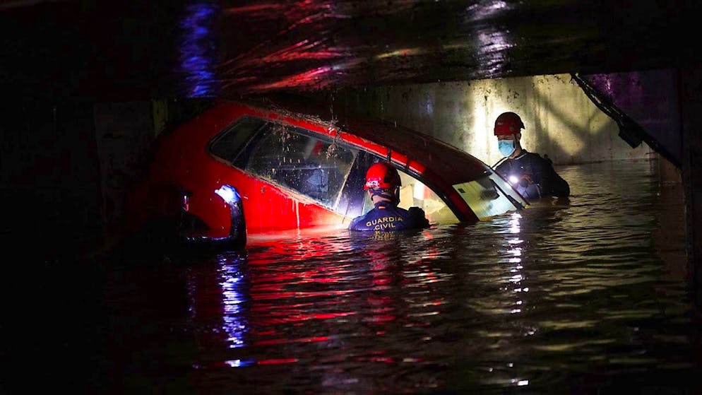 Helpers check cars in an underground parking garage after the floods in Spain. Photo: Alberto Saiz/AP
