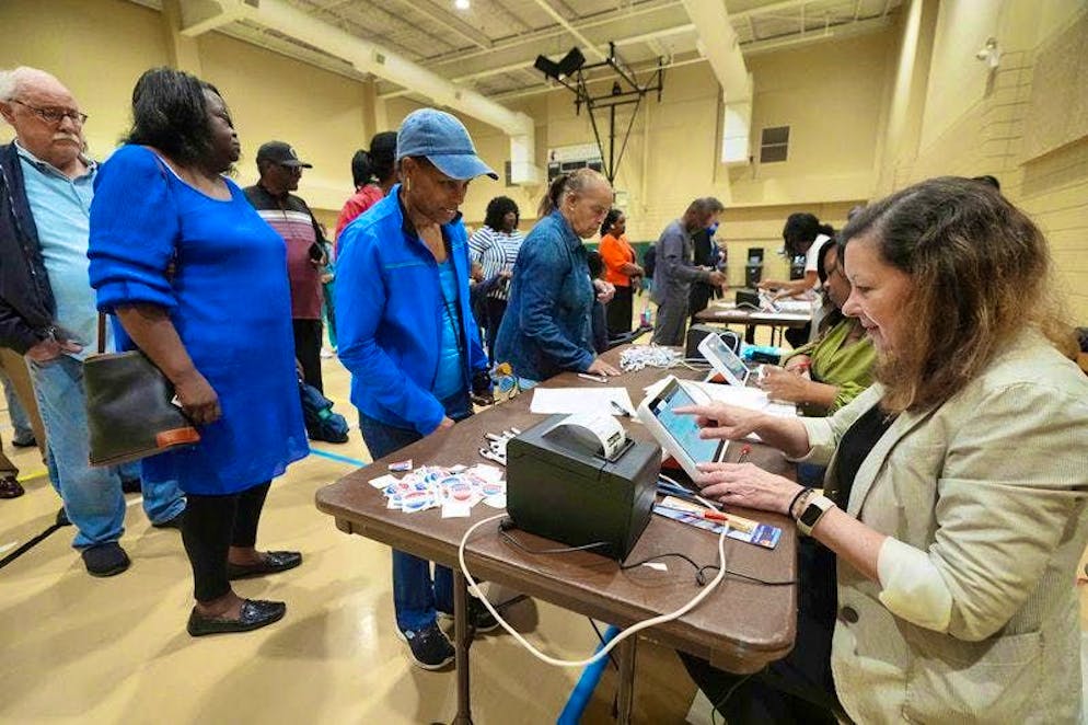 Trump o Harris? Il giorno delle elezioni negli Stati Uniti. Un addetto al seggio elettorale a nord di Jackson registra elettronicamente un elettore di prima mattina.