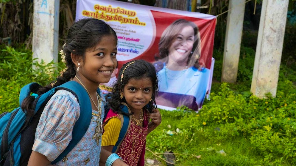 Scolari passano davanti a un poster con il volto di Kamala Harris.