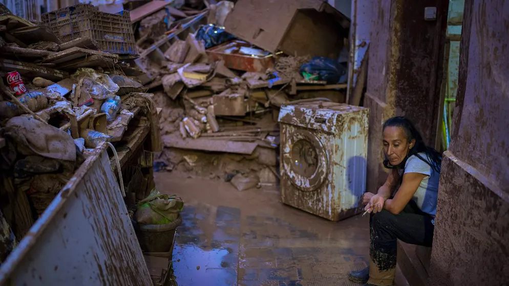 Eine Frau sitzt in Paiporta in der Region Valencia neben ihren aus dem Haus gespülten und geräumten Habseligkeiten. (5. November 2024)