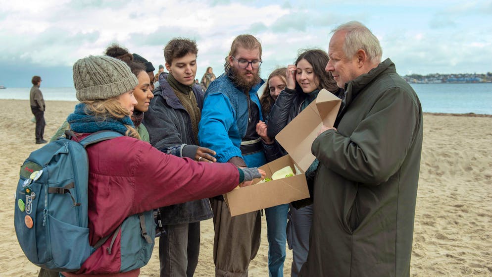 «Tatort» im Check: Ist eine KI als Mörderin wirklich möglich?. Der «nette Onkel» Borowski (Axel Milberg, rechts) verteilt frische Brötchen an die Umweltaktivisten am Strand (mit Johanna Götting, links).