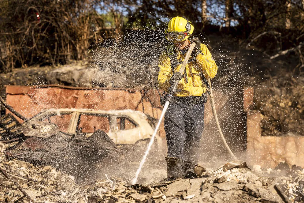 Le pompier Curtis Kabey arrose les points chauds d'une maison détruite par l'incendie de Mountain Fire à Camarillo, en Californie, le vendredi 8 novembre 2024. (AP Photo/Noah Berger)