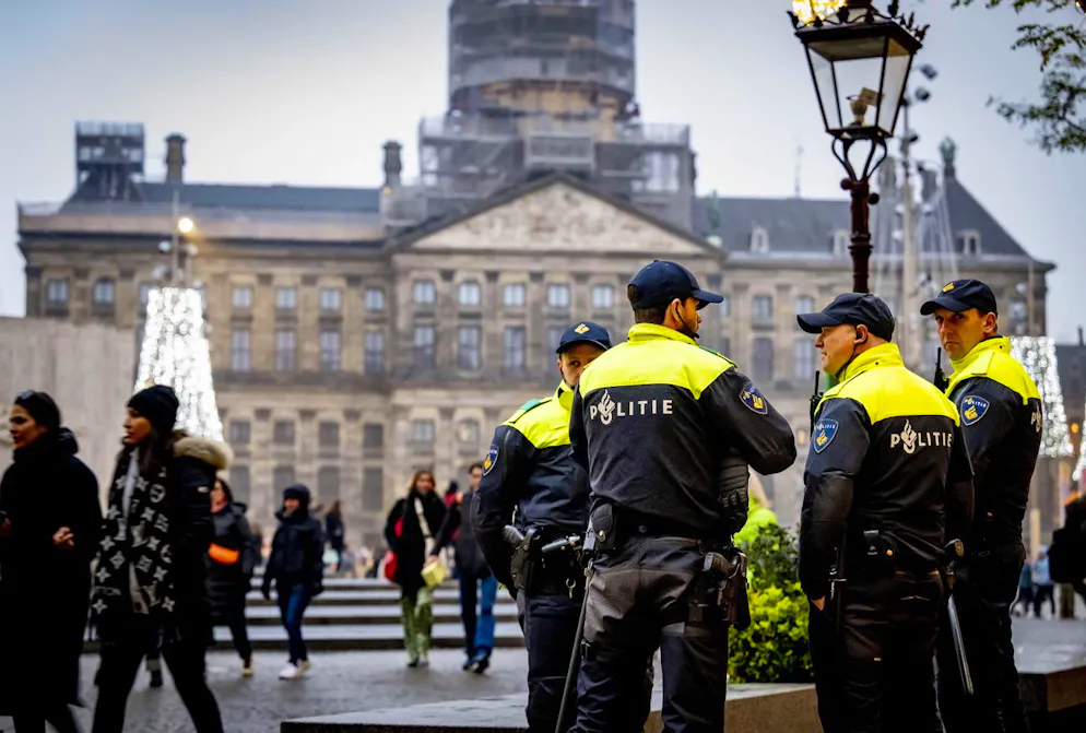 Des personnes passent devant une voiture de police alors que des officiers montent la garde sur la place du Dam à Amsterdam, Pays-Bas, 09 novembre 2024.