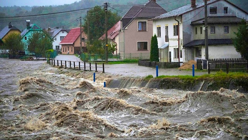ARCHIVE - The Bela River, churned up by floods, rushes past houses in the Czech Republic. Photo: Petr David Josek/AP/dpa