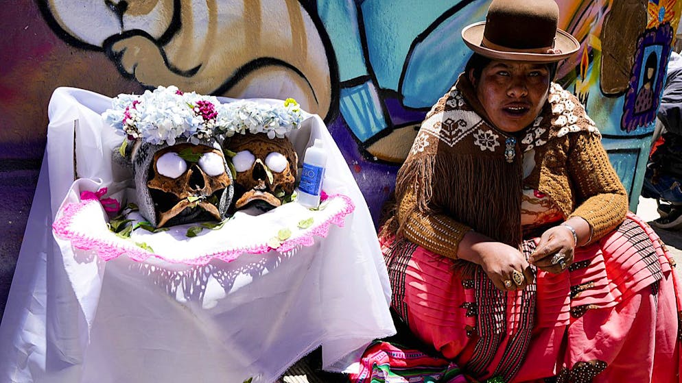 Una donna è seduta accanto ai teschi umani decorati alla festa annuale delle «Ñatitas».