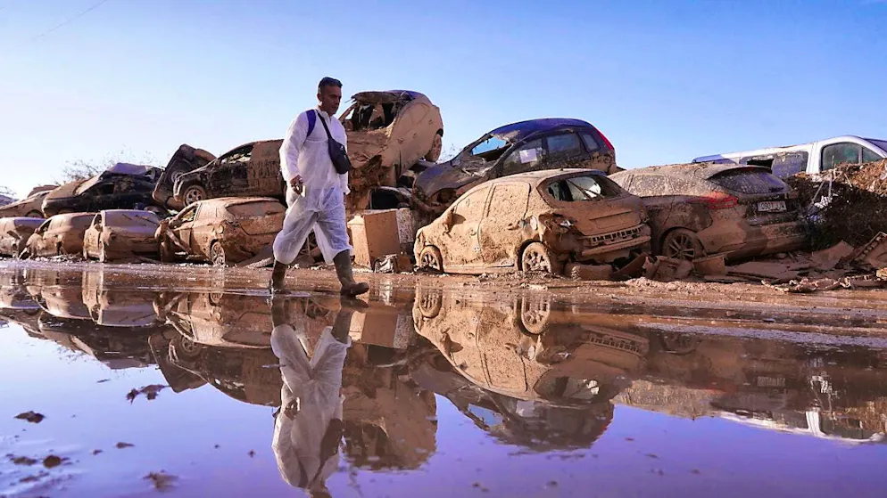 dpatopbilder - A man walks past piled up cars after floods left devastation and hundreds dead and missing in Catarroja in the Valencia region of Spain. Photo: Alberto Saiz/AP