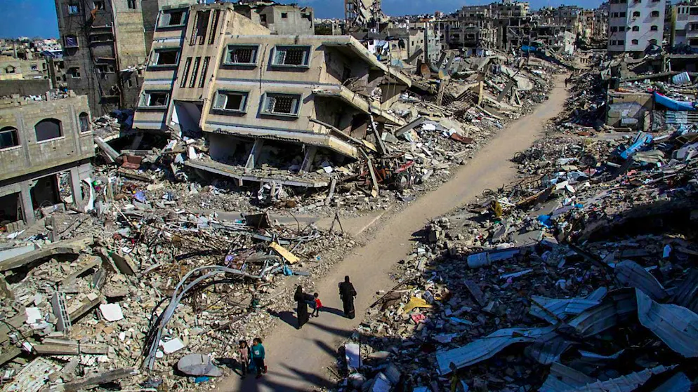ARCHIVE - People walk past the ruins of buildings destroyed by Israeli air strikes in the Jabalia refugee camp. Photo: Mahmoud Issa/dpa