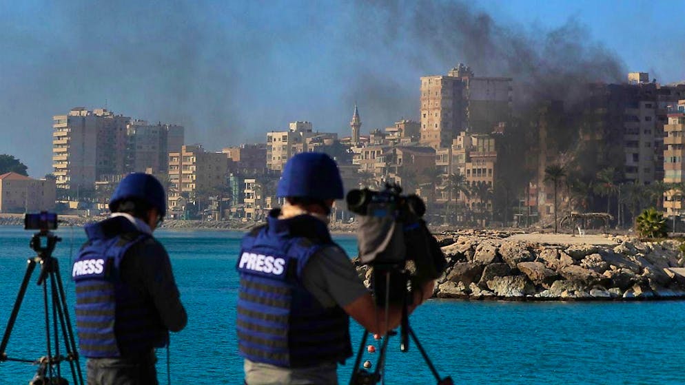 ARCHIVE - Journalists film and photograph the site of the attack, where smoke rises from buildings hit by Israeli airstrikes in Tyre, southern Lebanon. Photo: Mohammad Zaatari/AP/dpa