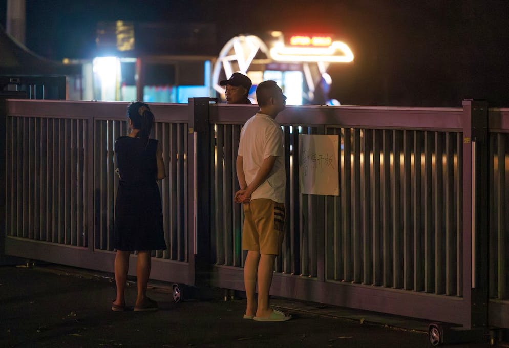 Des personnes se tiennent près d'une clôture gardée du centre sportif de Zhuhai à Zhuhai, Chine, 12 novembre 2024. Selon les médias d'État, au moins 35 personnes ont été tuées et 43 autres gravement blessées dans la soirée du 11 novembre après qu'une voiture a percuté des piétons dans un centre sportif à Zhuhai, dans la province de Guangdong. Selon la police, un suspect âgé de 62 ans est soigné à l'hôpital après s'être blessé.