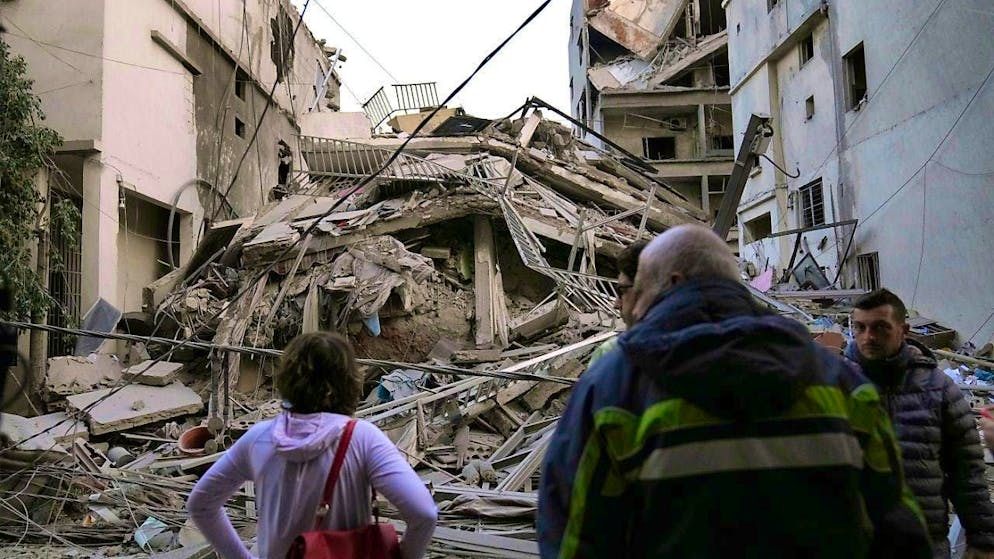 Residents look at their destroyed building, which was hit by an Israeli airstrike in Dahieh, a southern suburb of the Lebanese capital. Photo: Hussein Malla/AP/dpa