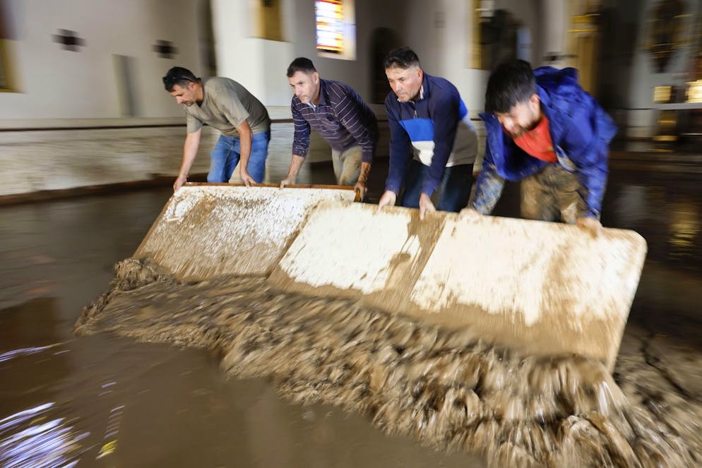 Des habitants retirent l'eau et la boue de l'église Encarnacion, après qu'une dépression isolée de haute altitude ait frappé la région, dans le village de Benamargosa, Malaga, sud de l'Espagne, le 14 novembre 2024. Une nouvelle DANA (dépression isolée de haute altitude) a touché le sud et l'est de l'Espagne, provoquant des inondations dans la province de Malaga.