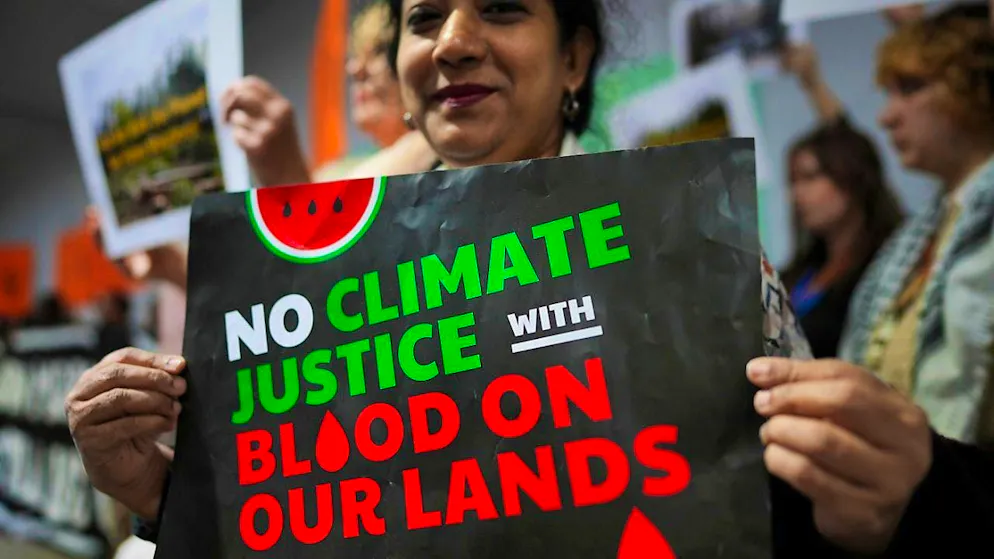 Activists with signs reading "No Climate Justice with Blood on our Lands" take part in a demonstration for climate justice at the Cop29 climate summit. Photo: Peter Dejong/AP/dpa