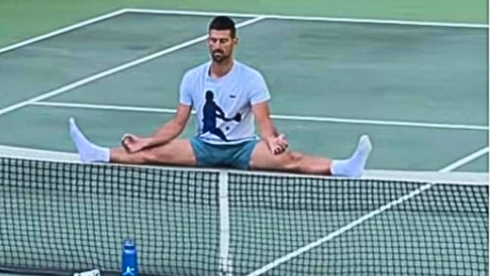 Novak Djokovic a gambe completamente divaricate, ma sulla rete del campo di allenamento. Un fake?
