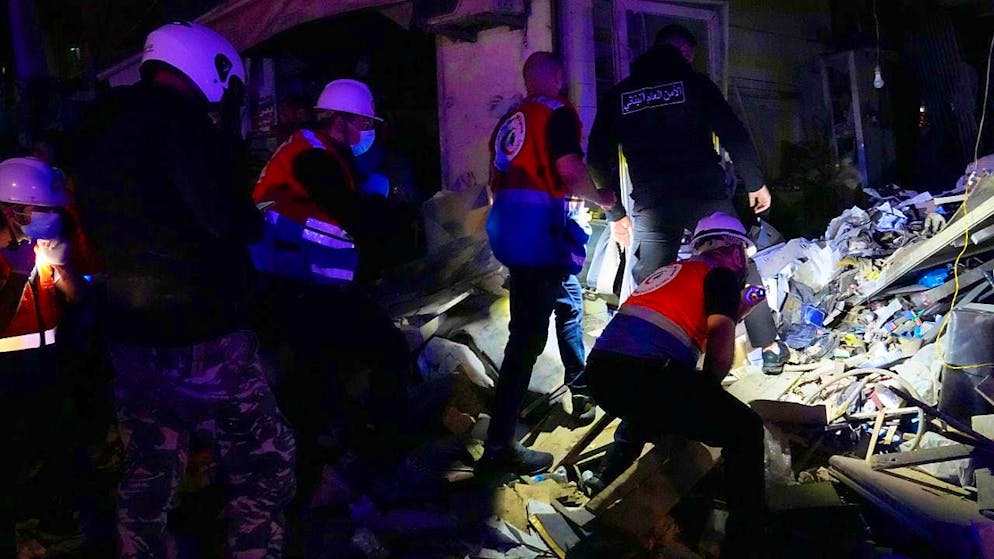 Rescue workers and police officers search for victims of an Israeli airstrike. Photo: Hussein Malla/AP/dpa