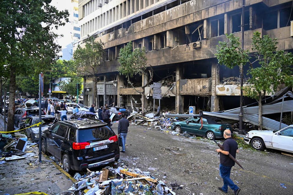 Des personnes marchent devant des magasins endommagés à la suite d'une frappe aérienne israélienne dans la rue Mar Elias, Beyrouth, Liban, 18 novembre 2024. Selon le ministère libanais de la Santé, deux personnes ont été tuées et vingt-deux autres ont été blessées dans l'incident.