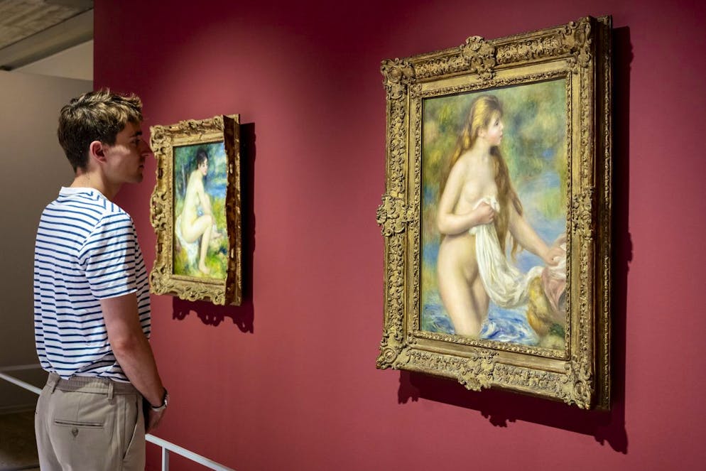 Une personne regarde les tableaux "Femme nue dans un paysage" de l'artiste Pierre-Auguste Renoir et "Baigneuse aux cheveux longs" de l'artiste Pierre-Auguste Renoir lors de l'exposition de la Fondation Gianadda "Cezanne - Renoir, Regard croises, Chefs-d'oeuvre des Musées de l'Orangerie et d'Orsay" le jeudi 11 juillet 2024 à Martigny. (KEYSTONE/Jean-Christophe Bott)