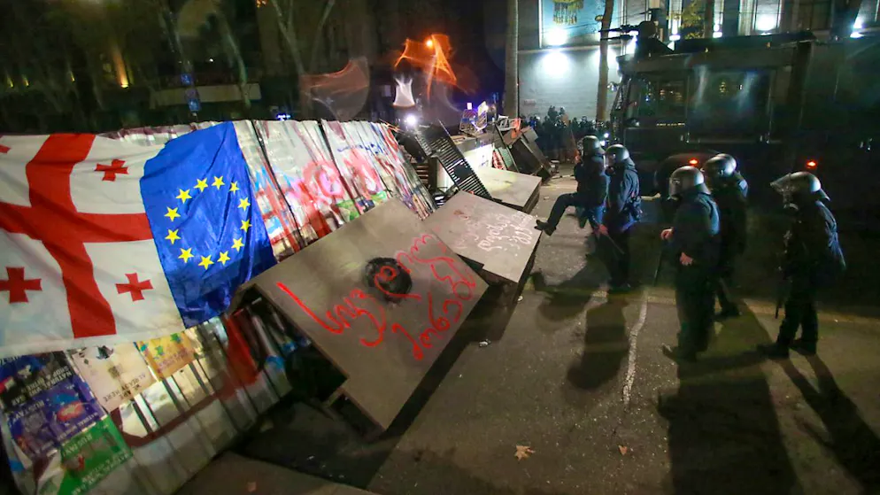 Polizisten neben einer Barrikade, die von Demonstranten während einer Kundgebung vor dem Parlamentsgebäude errichtet wurde. Foto: Zurab Tsertsvadze/AP/dpa
