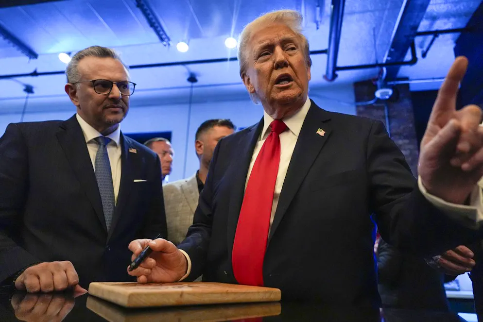 Il candidato repubblicano alle presidenziali, l'ex presidente Donald Trump, firma autografi mentre Massad Boulos ascolta la visita al Great Commoner, venerdì 1 novembre 2024, a Dearborn, Michigan