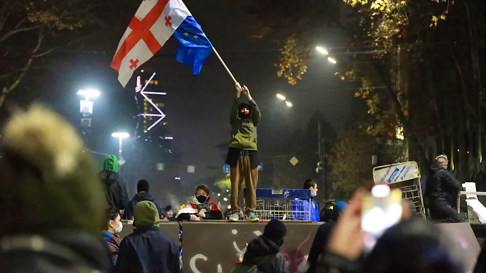 dpatopbilder - Ein Demonstrant steht mit georgischen National- und EU-Flaggen während einer Kundgebung vor dem Parlamentsgebäude in Tiflis. Foto: Zurab Tsertsvadze/AP/dpa