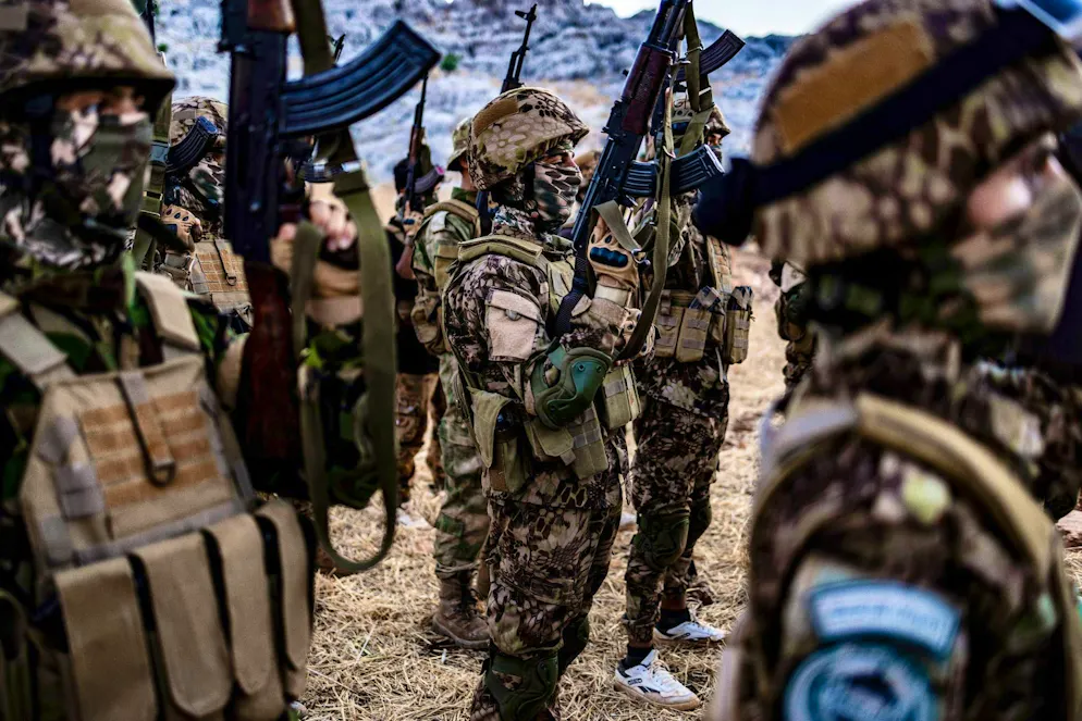 Fighters from the Islamist militant group HTS take part in a military maneuver.