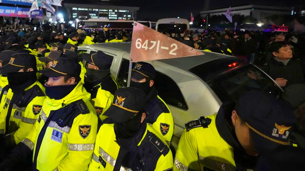 Militärfahrzeuge sind von Polizeibeamten vor der Nationalversammlung umgeben.