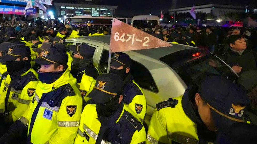 Military vehicles are surrounded by police officers outside the National Assembly.