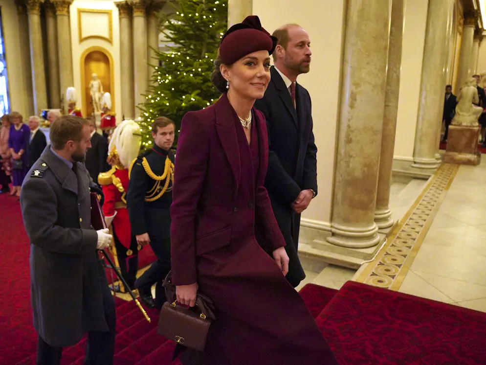 Kate en bordeaux. Kate a opté pour une tenue monochrome bordeaux, agrémentée de perles – des boucles d’oreilles pendantes et un collier ras de cou à quatre rangs ayant appartenu à Elizabeth II – pour apporter une touche de lumière.