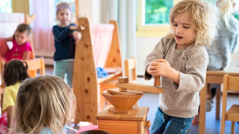 Ein Kind im Kindergarten mahlt Weizen, mithilfe einer Mühle. Der Kindergartenbesuch wird in Graubünden ab dem kommendem Schuljahr obligatorisch. (Archivbild)