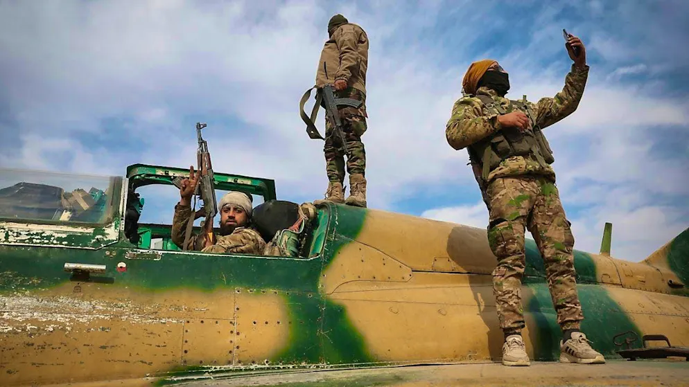 Syrian opposition fighters stand on a confiscated Syrian Air Force fighter plane at the military airport in Hama. Photo: Ghaith Alsayed/AP/dpa