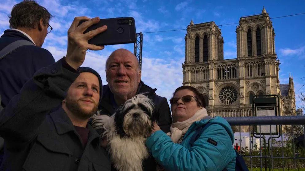 Tourists take photos in front of the renovated landmark in Paris on December 6.