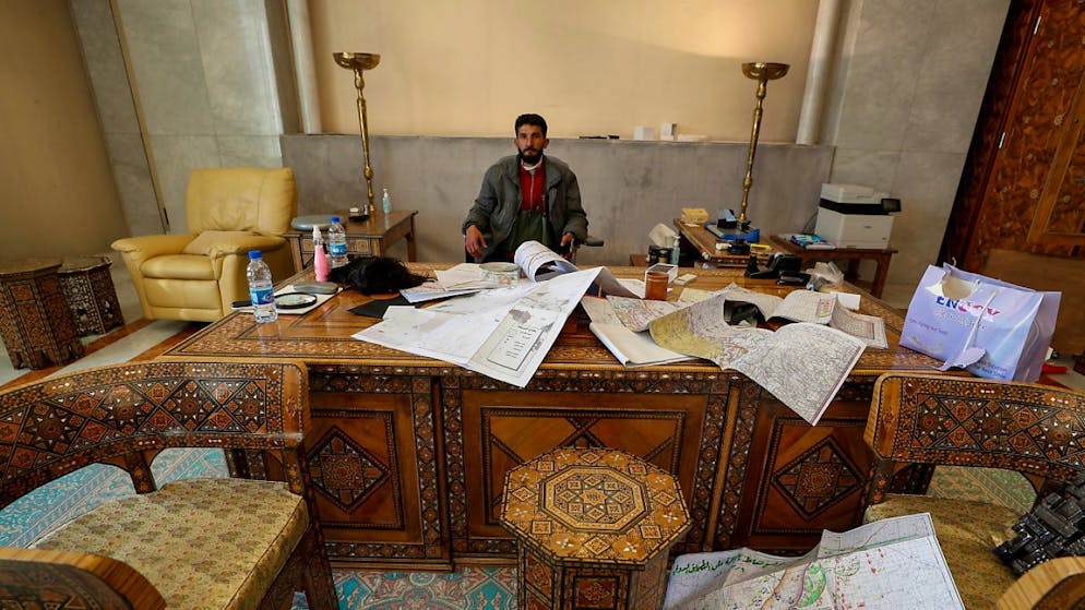 Ein syrischer Aufständischer sitzt in einem Büro im Präsidentenpalast nach dem Zusammenbruch der syrischen Regierung.