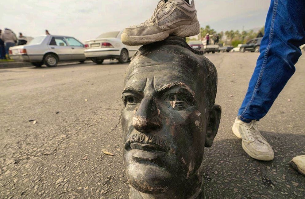 Overthrown: An opposition member poses with the head of a statue of Bashar's father Hafiz al-Assad in Damascus on December 8.